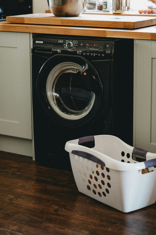 White laundry basket beside a front-load washing machine